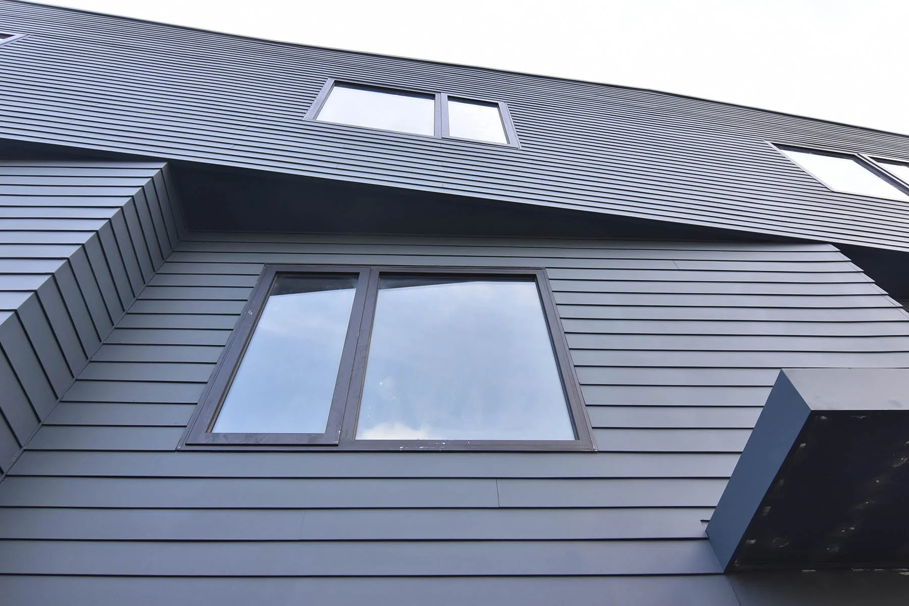 Architectural detail of slate-gray Hardy Board siding with angular roofline and window at Matilda Overlook